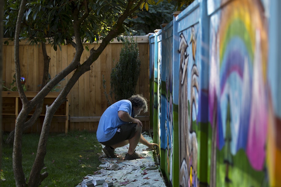 caption: Ryan Henry Ward works on a mural in the backyard of a home on Wednesday, September 8, 2021, in Shoreline. 