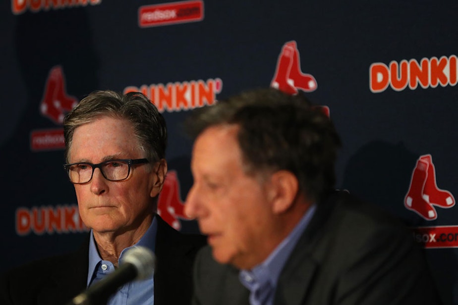 caption: Red Sox Owner John Henry looks on during a press conference addressing the departure of Alex Cora as manager of the Boston Red Sox at Fenway Park on Jan. 15, 2020 in Boston, Mass. A MLB investigation concluded that Cora was involved in the Houston Astros sign stealing operation in 2017 while he was the bench coach. (Maddie Meyer/Getty Images)