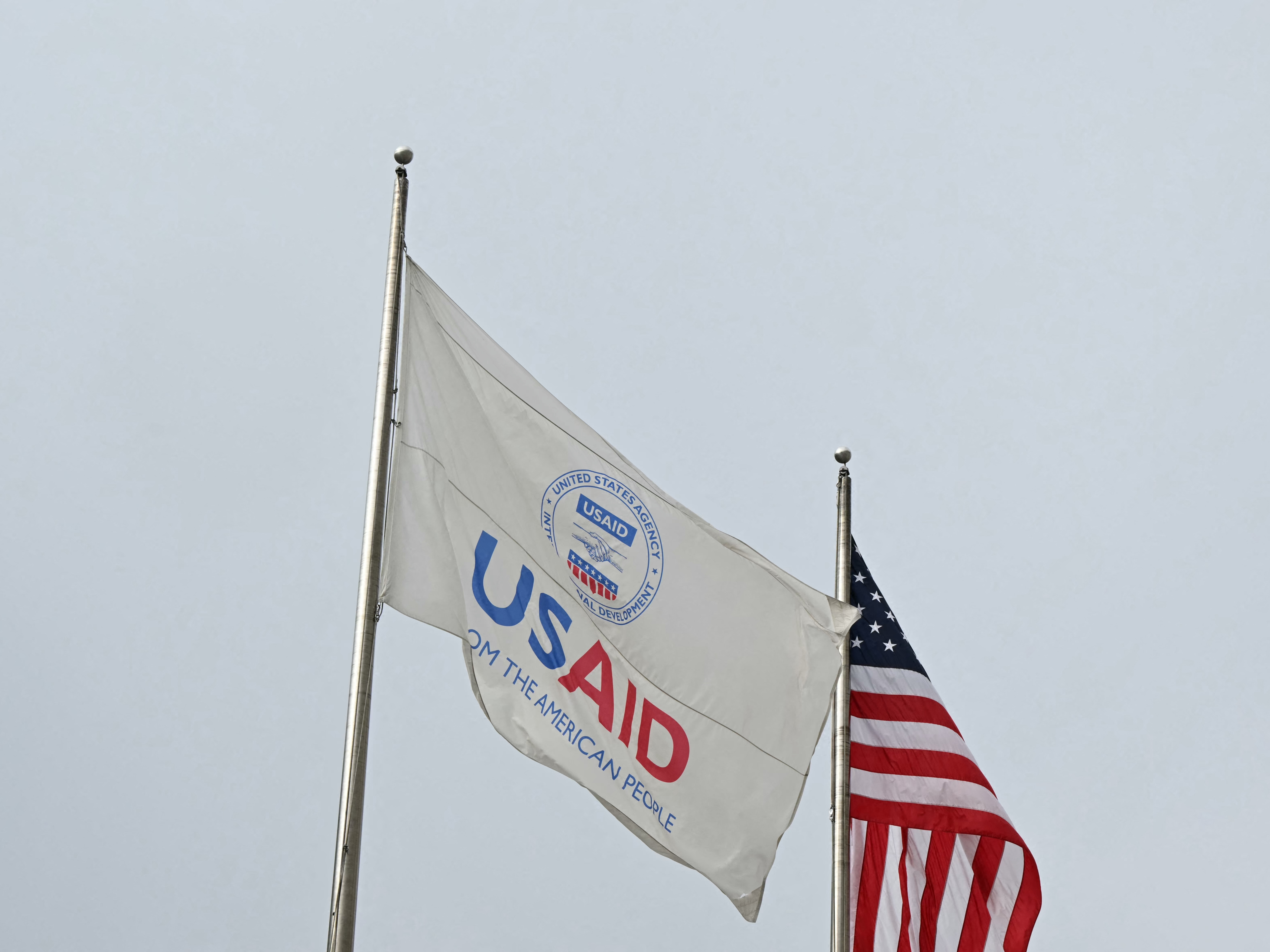 caption: A USAID and American flag outside of United States Agency for International Development headquarters in Washington, D.C., on Feb. 3, 2025.