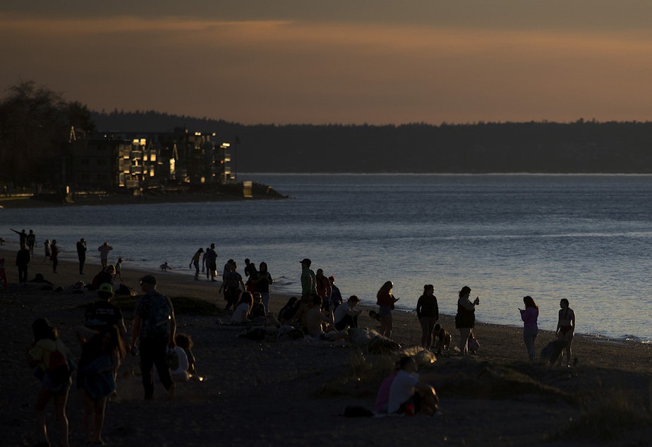 caption: People gather to watch the sunset on Tuesday, March 19, 2019, at Alki Beach Park in Seattle. 