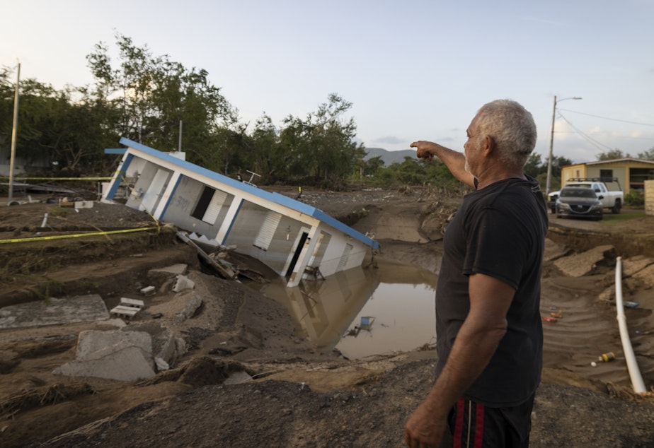 caption: A man on Wednesday points to a home that was collapsed by Hurricane Fiona at Villa Esperanza in Salinas, Puerto Rico.