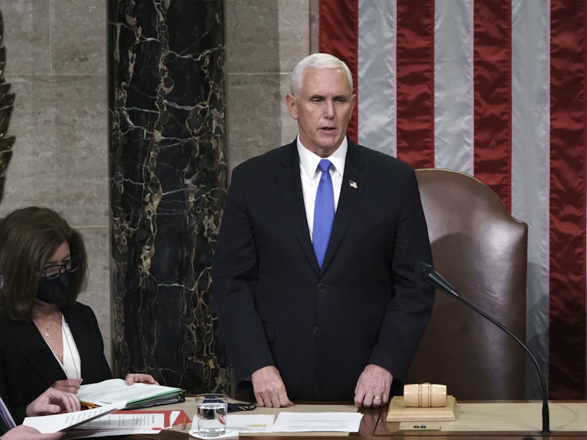 caption: Hours after rioters stormed the Capitol, Vice President Mike Pence listens after reading the final certification of Electoral College votes cast in November's presidential election.