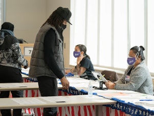 caption: Poll workers help voters get ready to cast their ballots on Nov. 3 in Atlanta. State lawmakers are now considering legislation that could roll back some laws that made it easier for voters to cast ballots by mail.