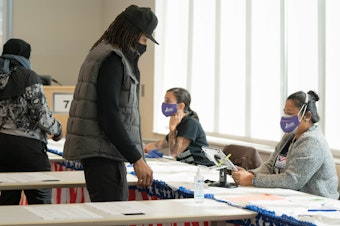 caption: Poll workers help voters get ready to cast their ballots on Nov. 3 in Atlanta. State lawmakers are now considering legislation that could roll back some laws that made it easier for voters to cast ballots by mail.