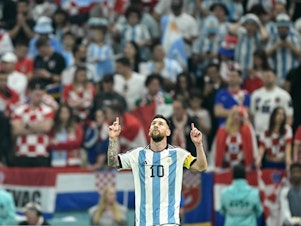 caption: Argentina forward Lionel Messi celebrates scoring his team's first goal from the penalty spot during the World Cup semifinal match between Argentina and Croatia in Qatar on December 13, 2022.