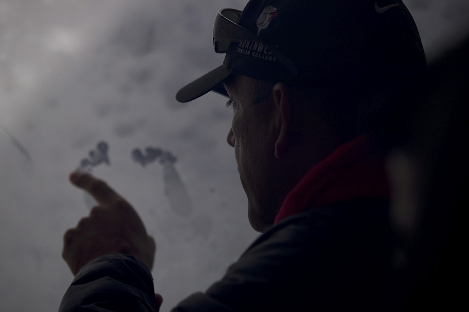 caption: Lummi Tribal Chairman Jay Julius uses the side of his fist and index finger to make what looks like feet on a window aboard King County Research Vessel SoundGuardian on Wednesday, April 10, 2019, after in the waters west of Bellingham. Lummi tribal members released one live chinook salmon into the Salish Sea on Wednesday as a spiritual offering to J17, an orca matriarch who has been ailing. 