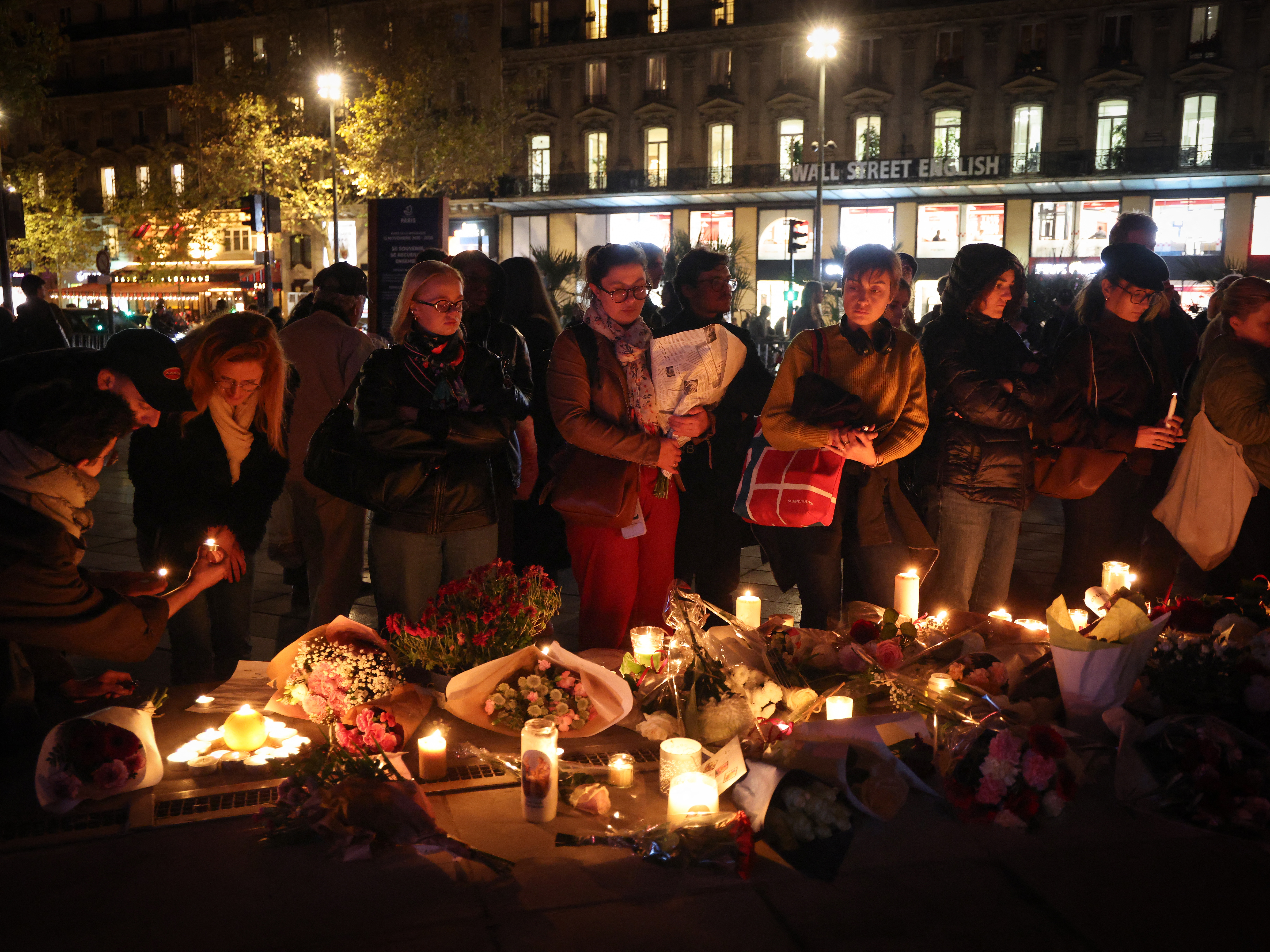 caption: People lay flowers and light candles in tribute to the victims of the 2015 Paris attacks at a temporary memorial at Place de la République in Paris on Wednesday.