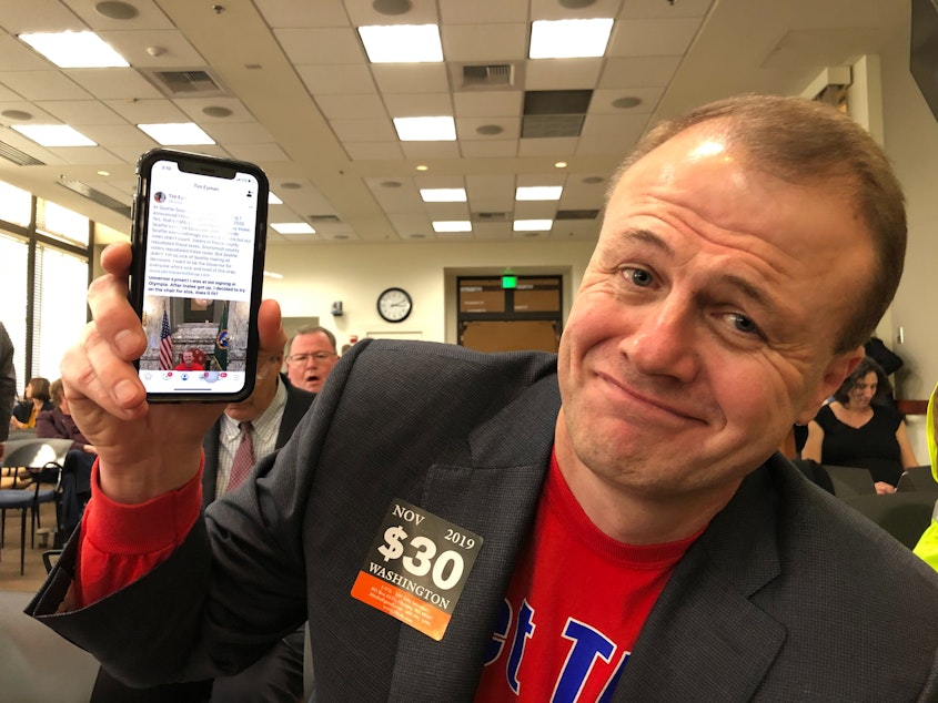 caption: Anti-tax activist Tim Eyman shows off a Facebook post announcing his run for governor.