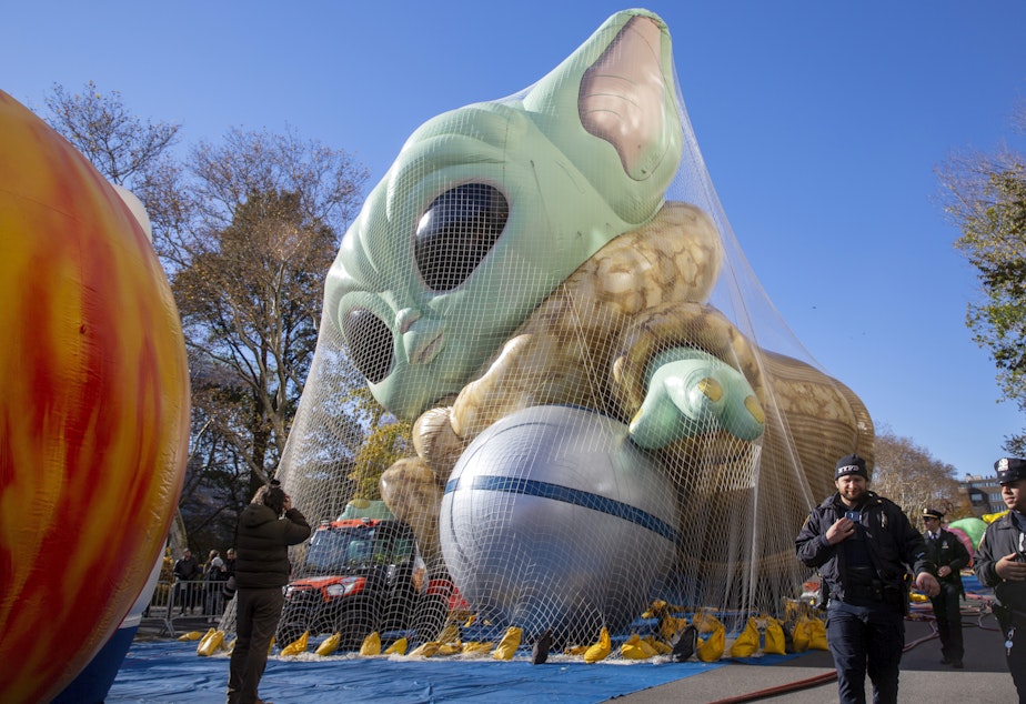 caption: Police walk by an inflated helium balloon of Grogu, also known as Baby Yoda, from the Star Wars show The Mandalorian, on Wednesday in New York, as the balloon is readied for the Macy's Thanksgiving Day Parade on Thursday.