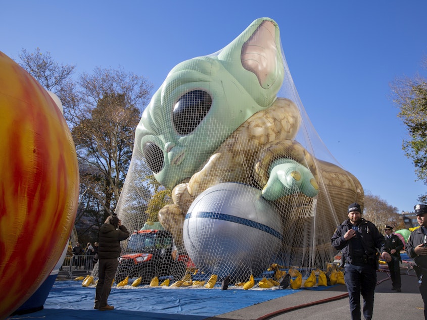 caption: Police walk by an inflated helium balloon of Grogu, also known as Baby Yoda, from the Star Wars show The Mandalorian, on Wednesday in New York, as the balloon is readied for the Macy's Thanksgiving Day Parade on Thursday.
