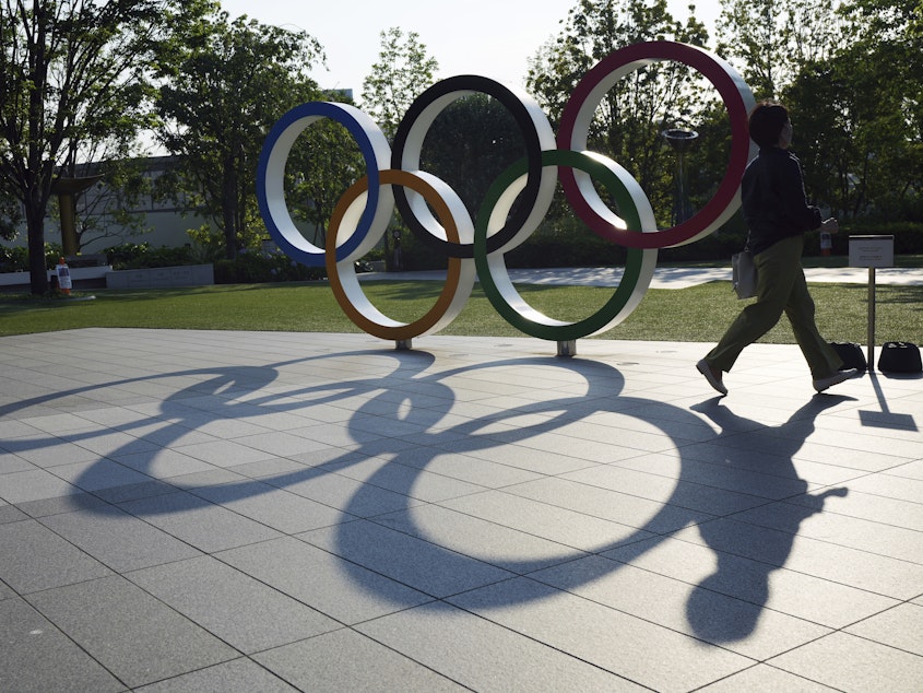 caption: A woman walks by the Olympic Rings near the National Stadium in Tokyo on June 9, 2021.