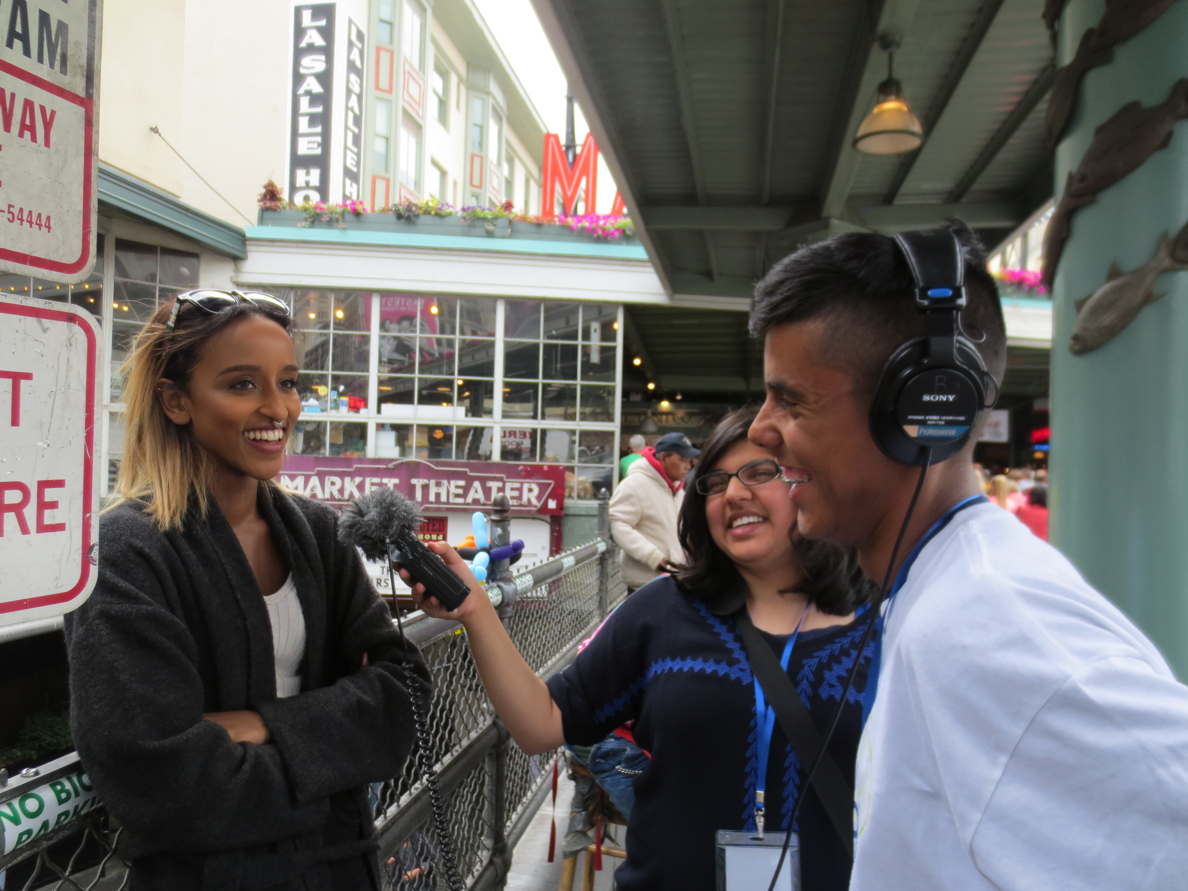 caption: RadioActive youth producers Mimansa Dogra and Gerardo Ramos ask questions of a passerby at Pike Place Market.