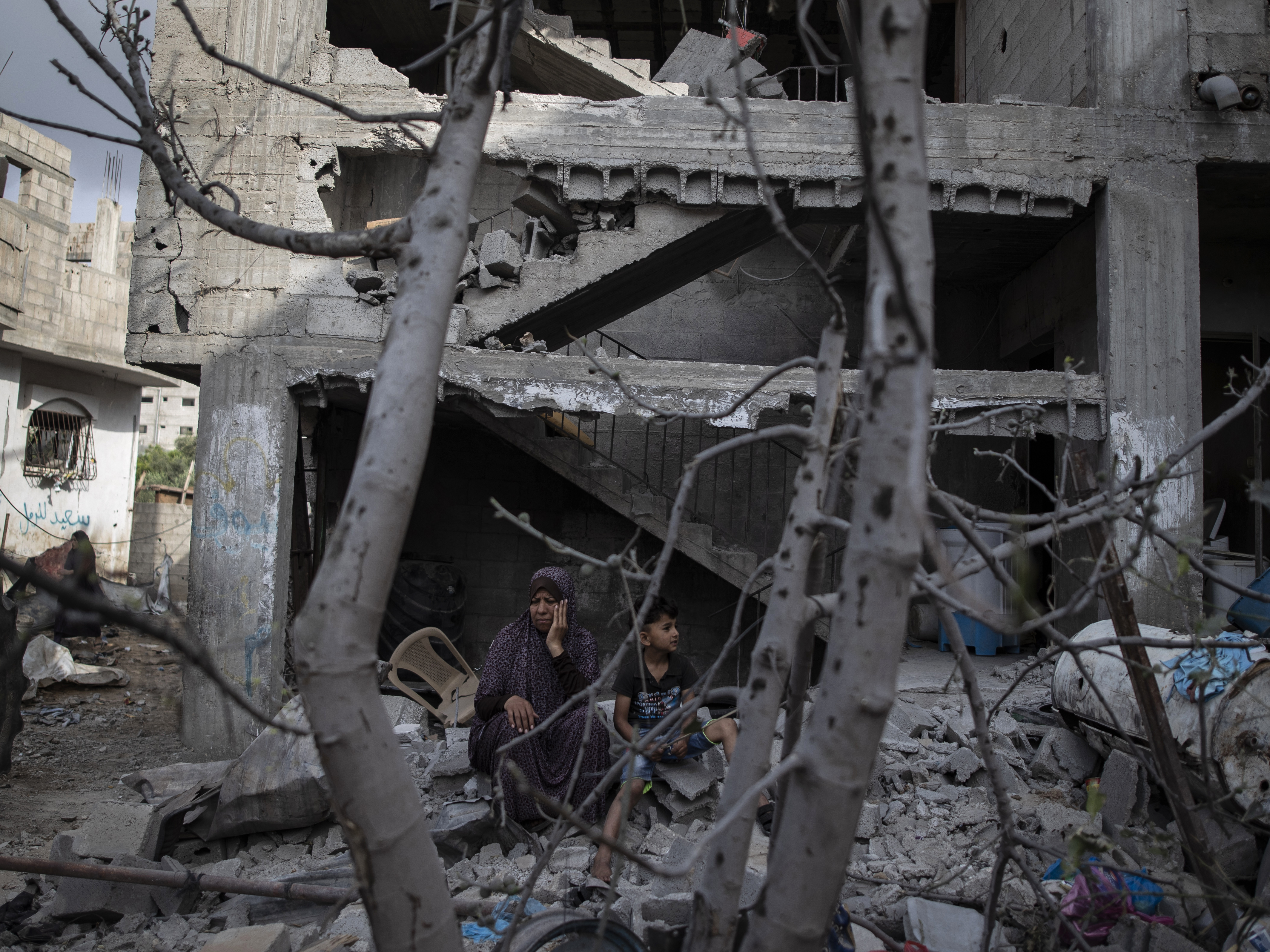 caption: A Palestinian woman sits with her son in front of her destroyed house in the town of Beit Hanoun, northern Gaza Strip, to which she returned following a cease-fire reached after an 11-day war between Gaza's Hamas rulers and Israel.