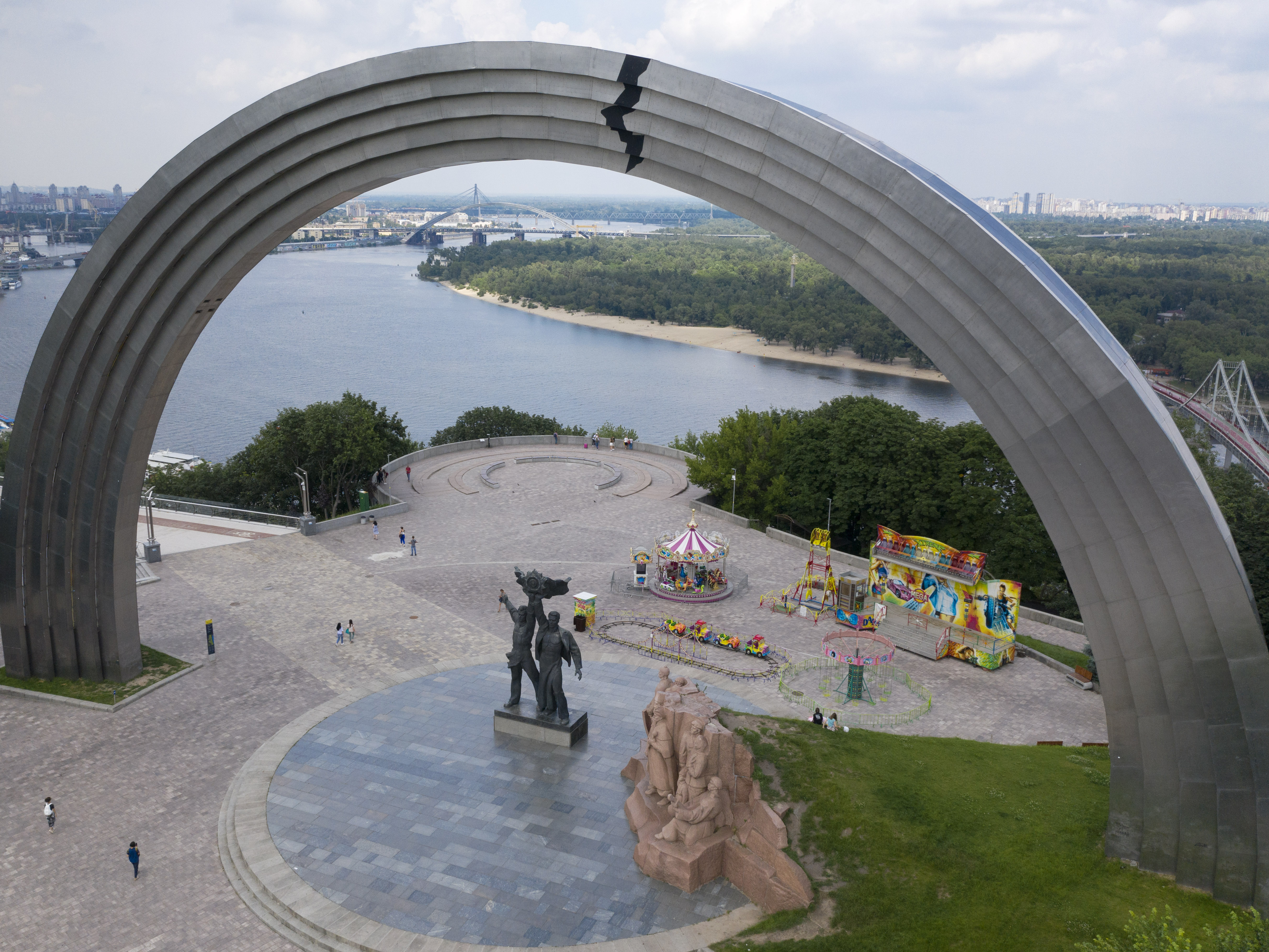 caption: People walk in a city park around a Soviet-era monument in Kyiv, Ukraine, in June 2020.