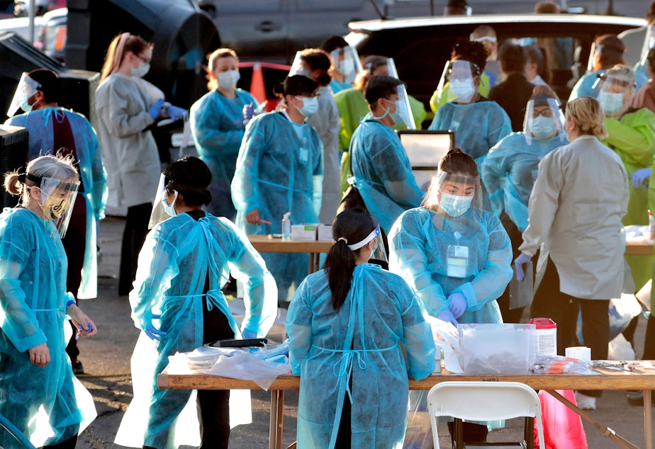 caption: Medical personnel prepare to test hundreds of people for the coronavirus. They lined up in vehicles last week in a Phoenix neighborhood.