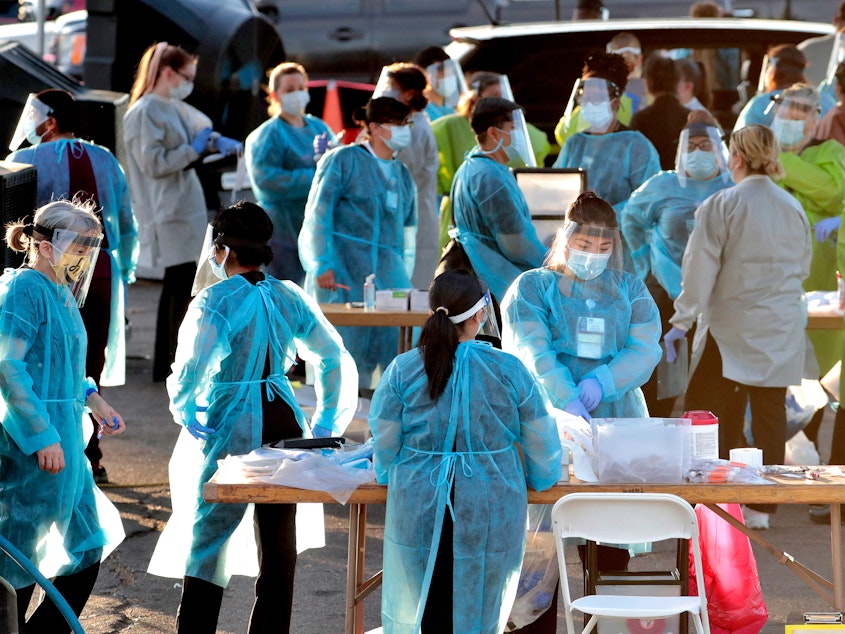 caption: Medical personnel prepare to test hundreds of people for the coronavirus. They lined up in vehicles last week in a Phoenix neighborhood.