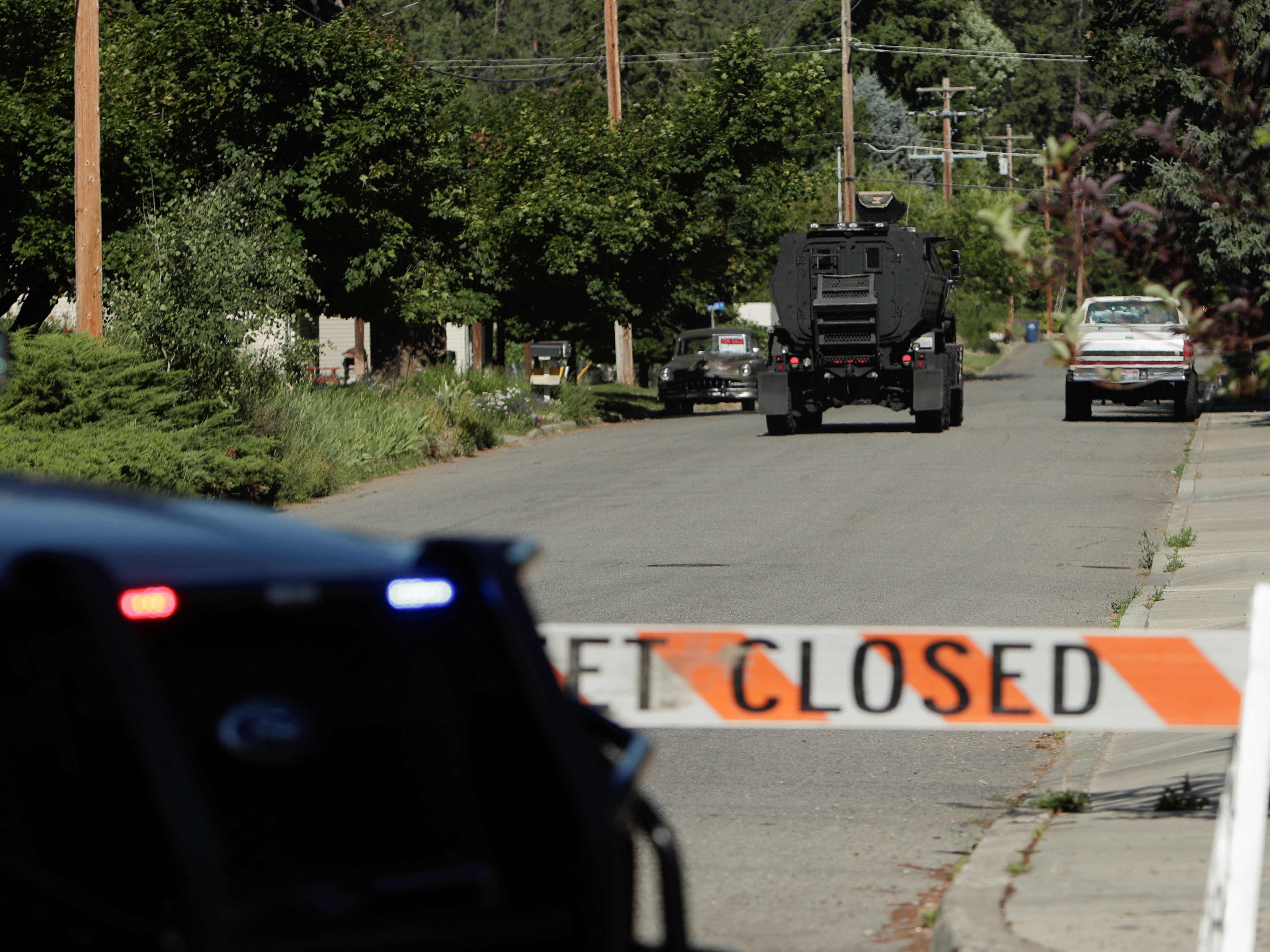 caption: An armored police vehicle travels towards an area where multiple firefighters were attacked when responding to a fire in the Canfield Mountain area on the outskirts of Coeur d'Alene, Idaho, on Sunday.