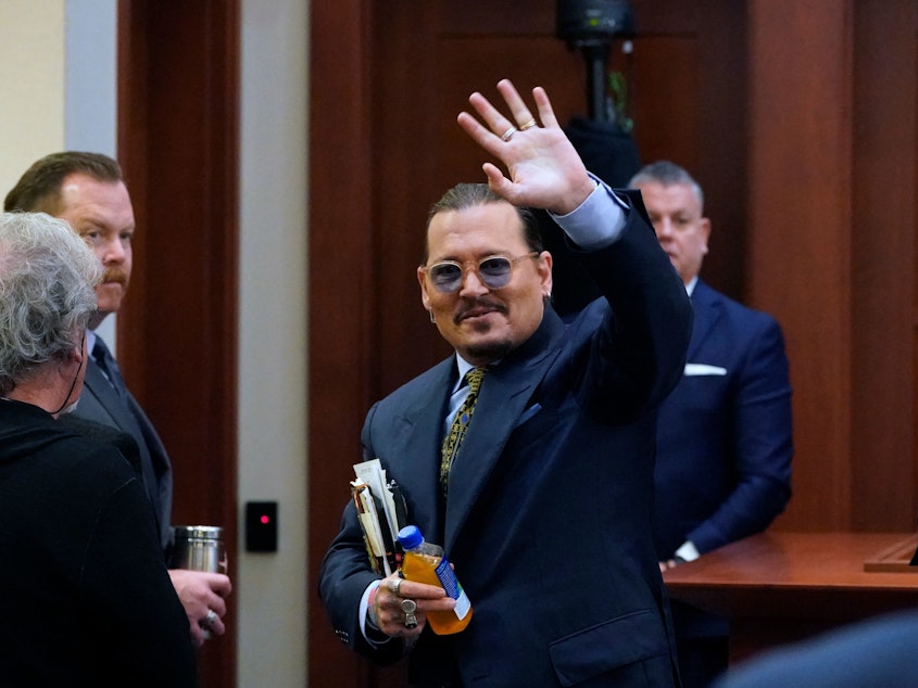 caption: Actor Johnny Depp waves to the gallery as he leaves for a break Monday during his defamation trial in Fairfax, Va. against his ex-wife, Amber Heard.
