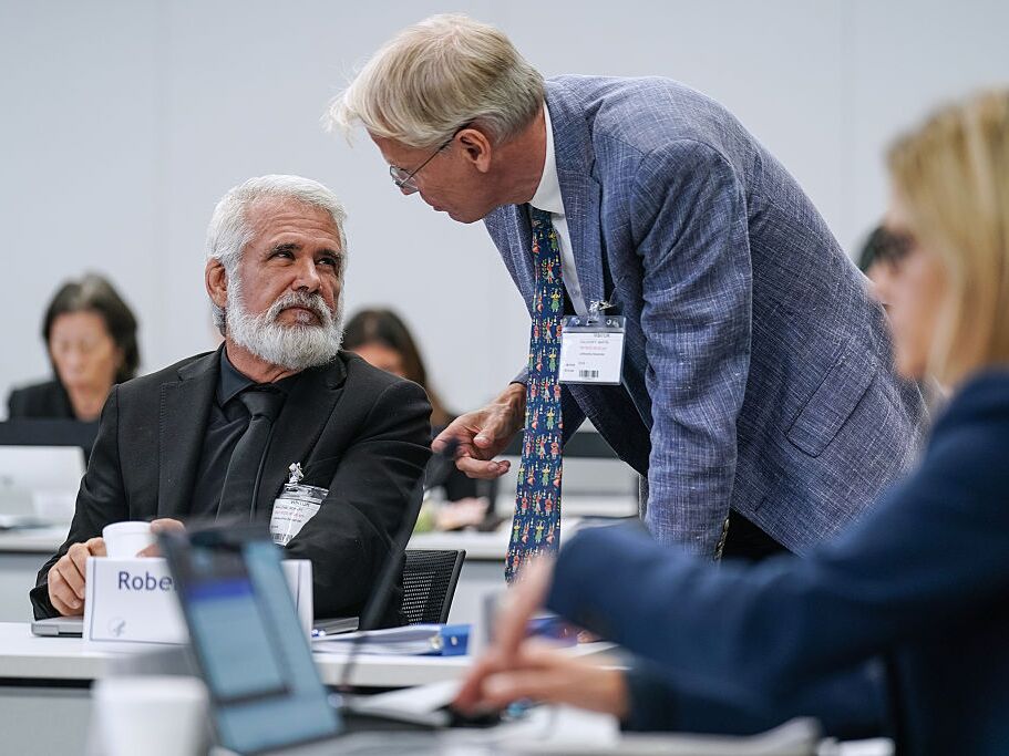 caption: Martin Kulldorff (right) speaks with Robert Malone during a meeting of the CDC's Advisory Committee on Immunization Practices on September 18, 2025 in Chamblee, Ga.