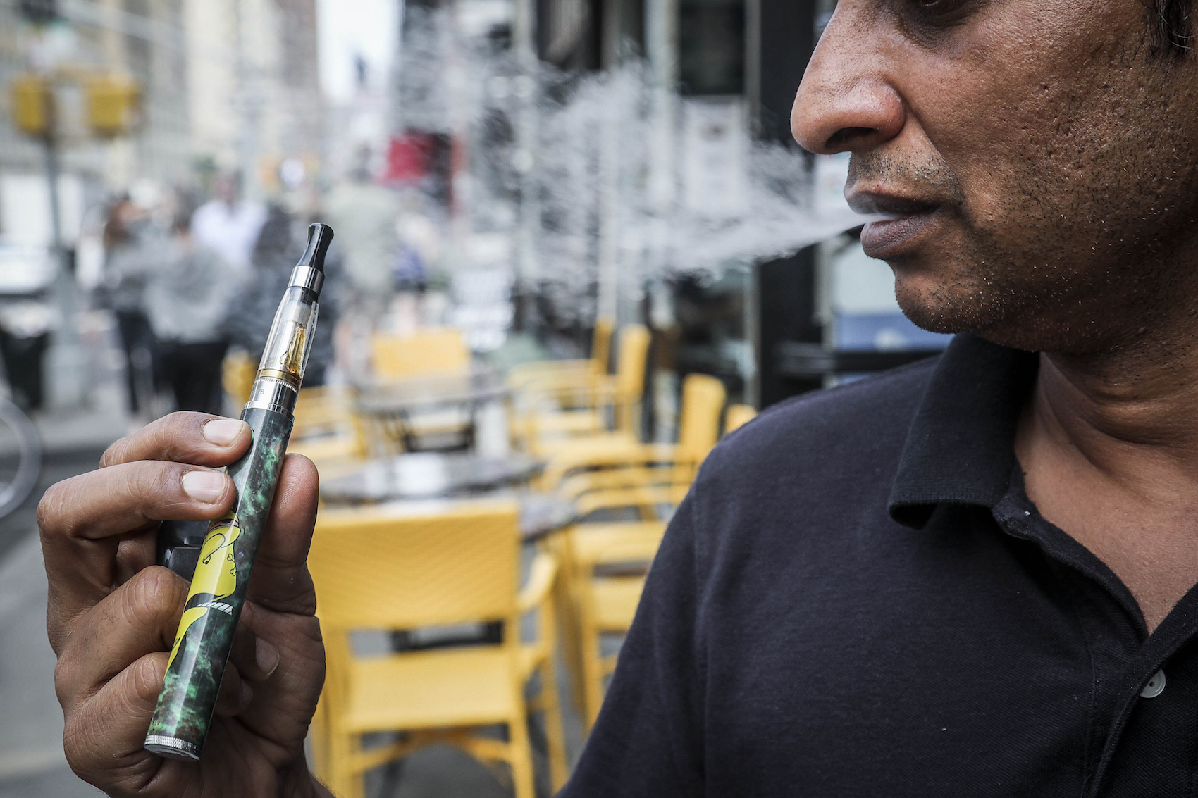 caption: Inam Rehman, manager of Jubilee Vape & Smoke Inc., vapes while discussing New York Gov. Andrew Cuomo's push to enact a statewide ban on the sale of flavored e-cigarettes amid growing health concerns, Monday Sept. 16, 2019, in New York. (Bebeto Matthews/AP)