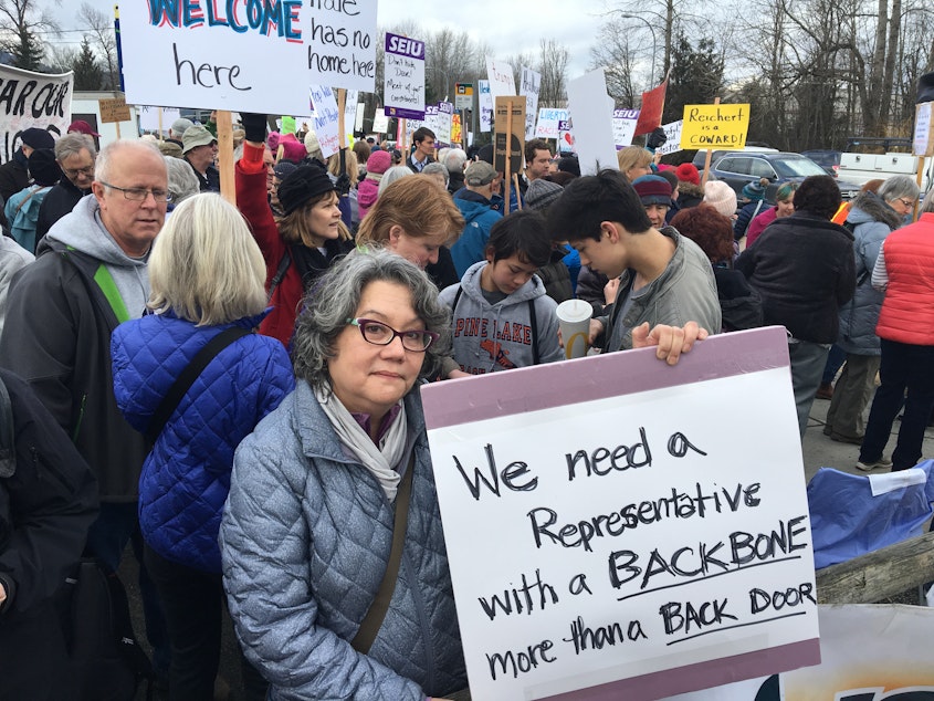 caption: Mardie Rhodes protests outside Rep. Dave Reichert's office in Issaquah in February.