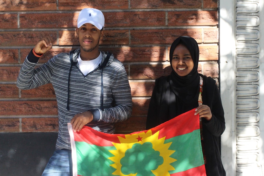 caption: Hosts Awal Ibrahim and Zubeyda Ahmed hold the Oromo flag. 