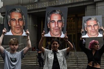 caption: A group of protesters hold photos of Jeffrey Epstein in front of a New York City federal courthouse in July 2019. A Southern District judge ruled this week that three lawsuits against banks that Epstein used can move forward.