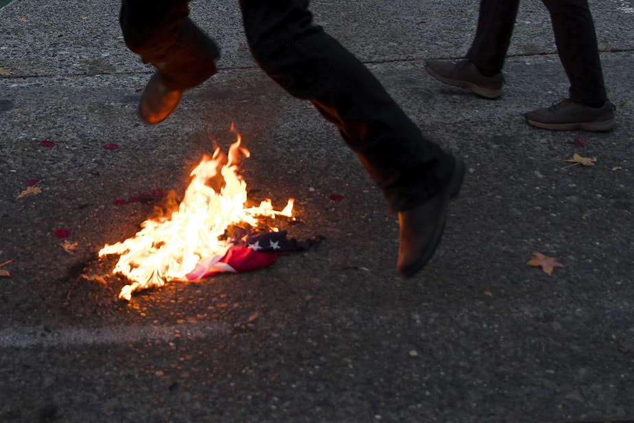 caption: A group of antifascist protesters burned an American flag as hundreds gathered during an impromptu celebration after Joe Biden was officially named the president elect on Saturday, November 7, 2020, at the intersection of 10th Avenue and East Pine Street in Seattle. 