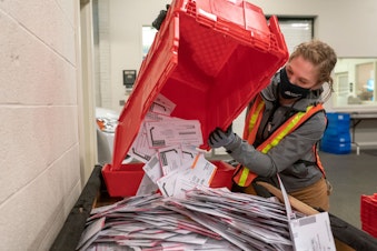 caption: Election worker Sarah Sladek empties a box of submitted ballots at the Multnomah County Elections Office on November 2, 2020 in Portland, Oregon. (Nathan Howard/Getty Images)
