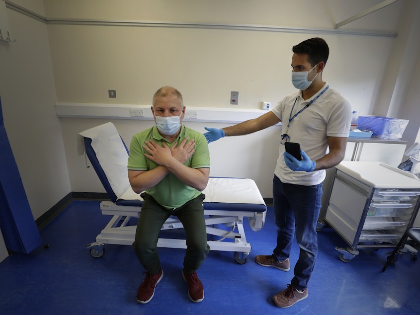 caption: Long COVID patient Gary Miller, left, receives treatment from physiotherapist Joan Del Arco at the Long COVID Clinic at King George Hospital in Ilford, London, in May.
