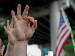 caption: A demonstrator makes the OK hand gesture believed to have white supremacist connotations during "The End Domestic Terrorism" rally at Tom McCall Waterfront Park on August 17, 2019 in Portland, Ore.
