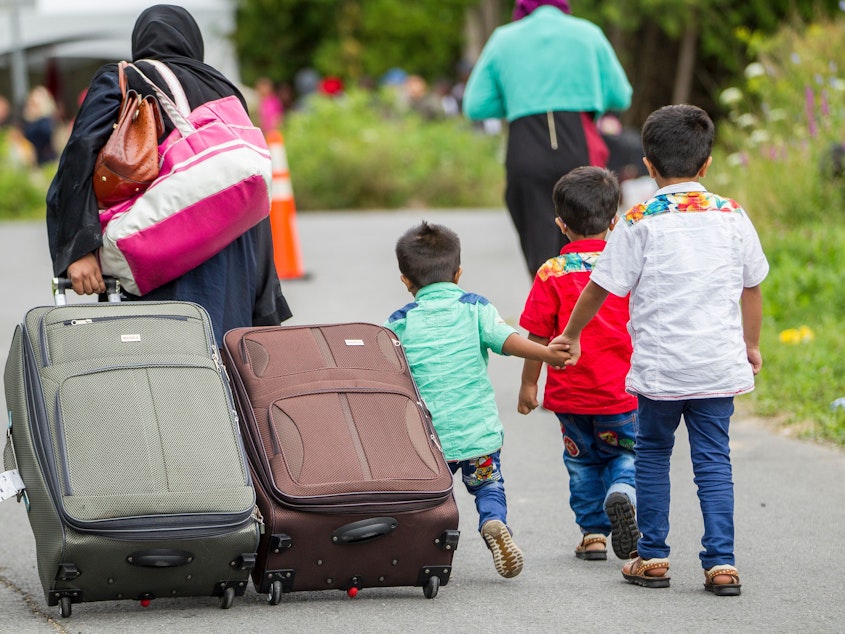 caption: Asylum seekers walk along Roxham Rd. in 2017, making their way towards the U.S.-Canada border. More than 50,000 migrants have entered Canada at irregular crossings since 2017.