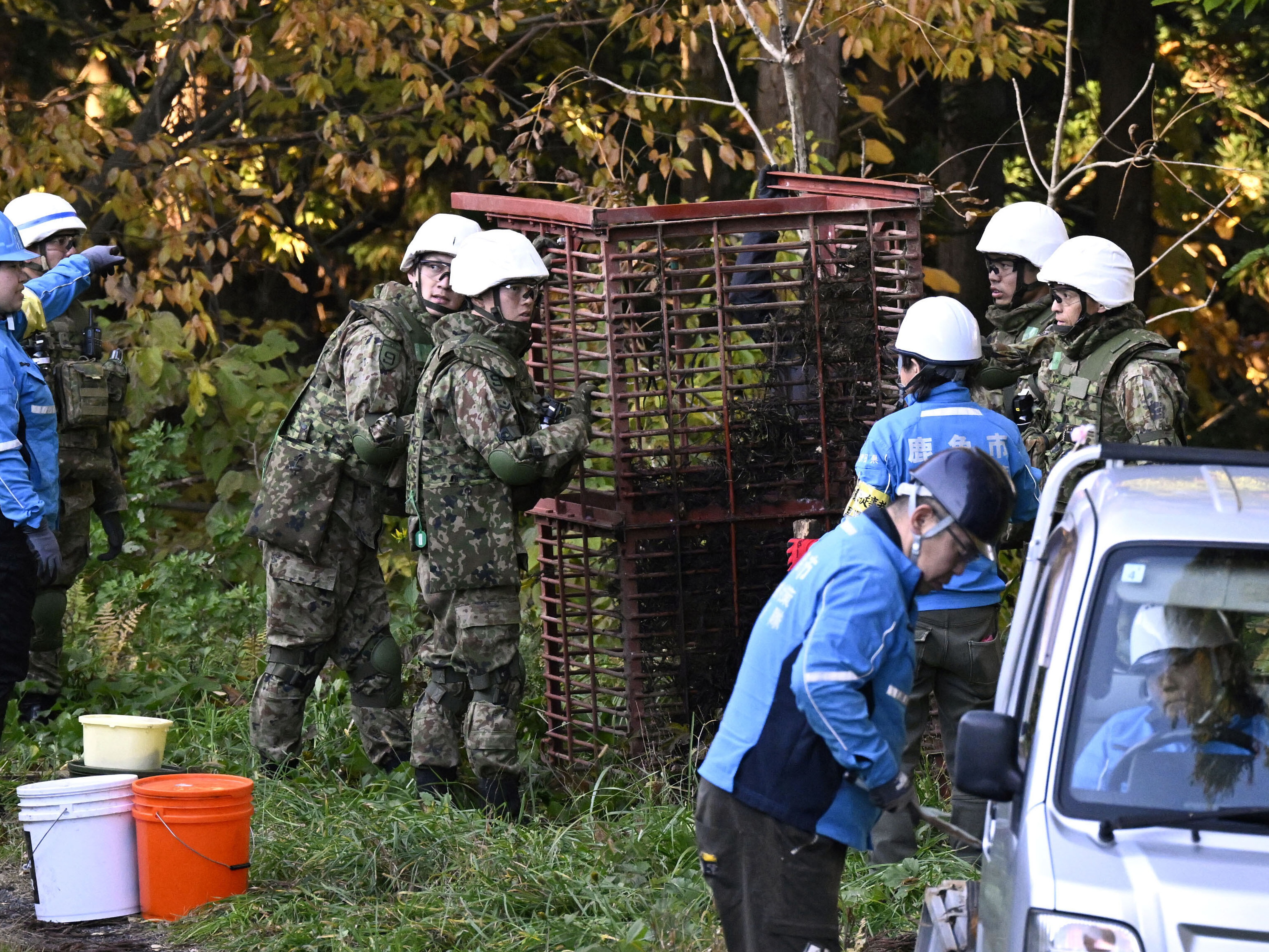 caption: Japan Ground Self-Defense Force members and others set up a box trap to capture bears in Kazuno, Akita prefecture, northern Japan on Wednesday.