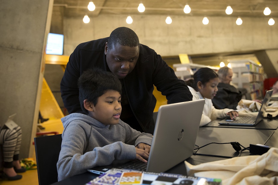 caption: Bryan Kelly helps his son Kingston Kelly, 10, with science homework at the Seattle Public Library Central branch on Thursday, January 2, 2020, on 4th Avenue in Seattle. As of January 2, all late fees for overdue books have ended. 