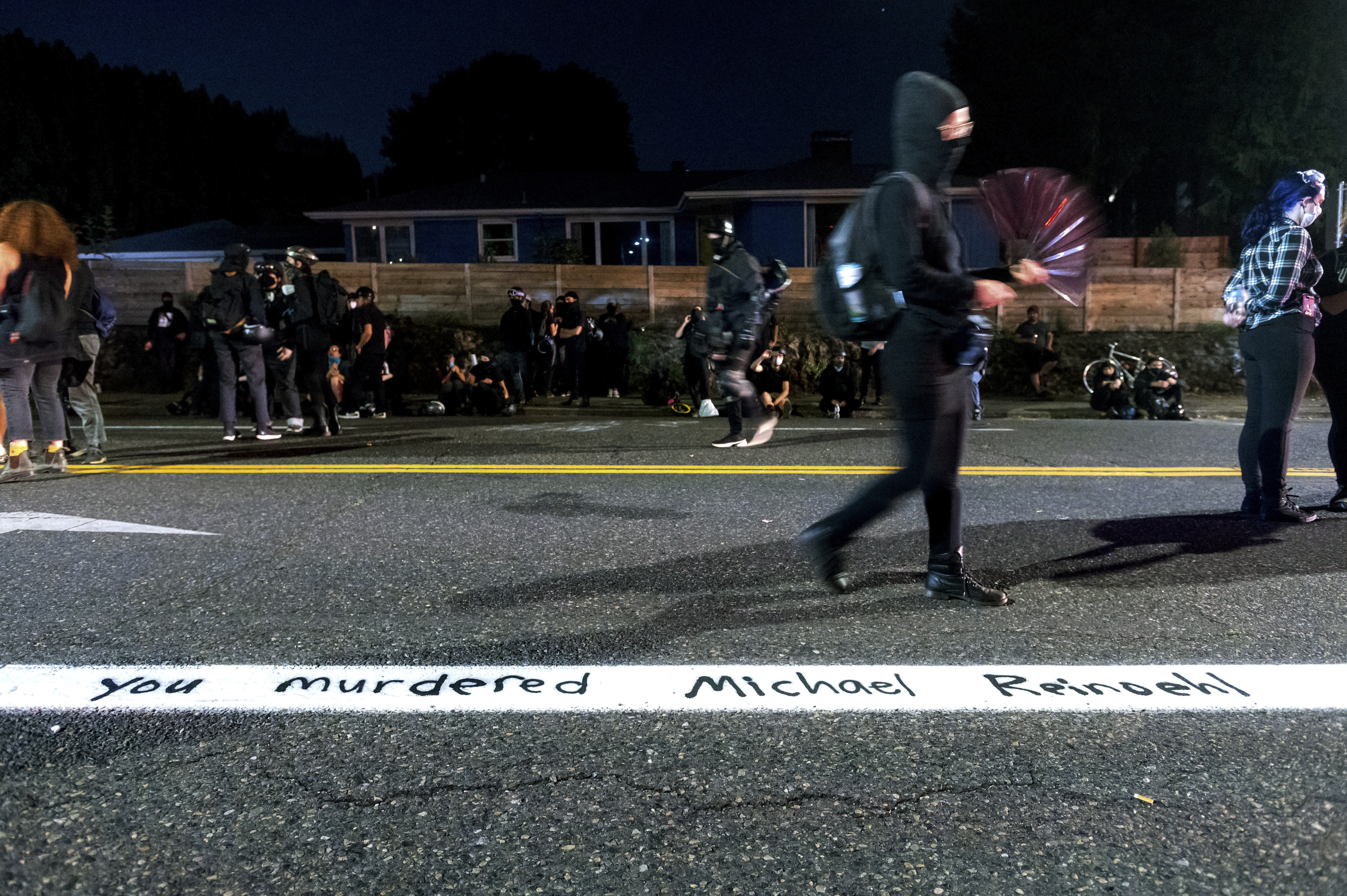 caption: A Black Lives Matter demonstrator passes writing referencing Michael Reinoehl in Portland, Ore., on Thursday, Sept. 3, 2020. Reinoehl, suspected of fatally shooting a supporter of a right-wing group, was killed earlier in the day as investigators moved in to arrest him, according to a senior Justice Department official. (AP Photo/Noah Berger)

