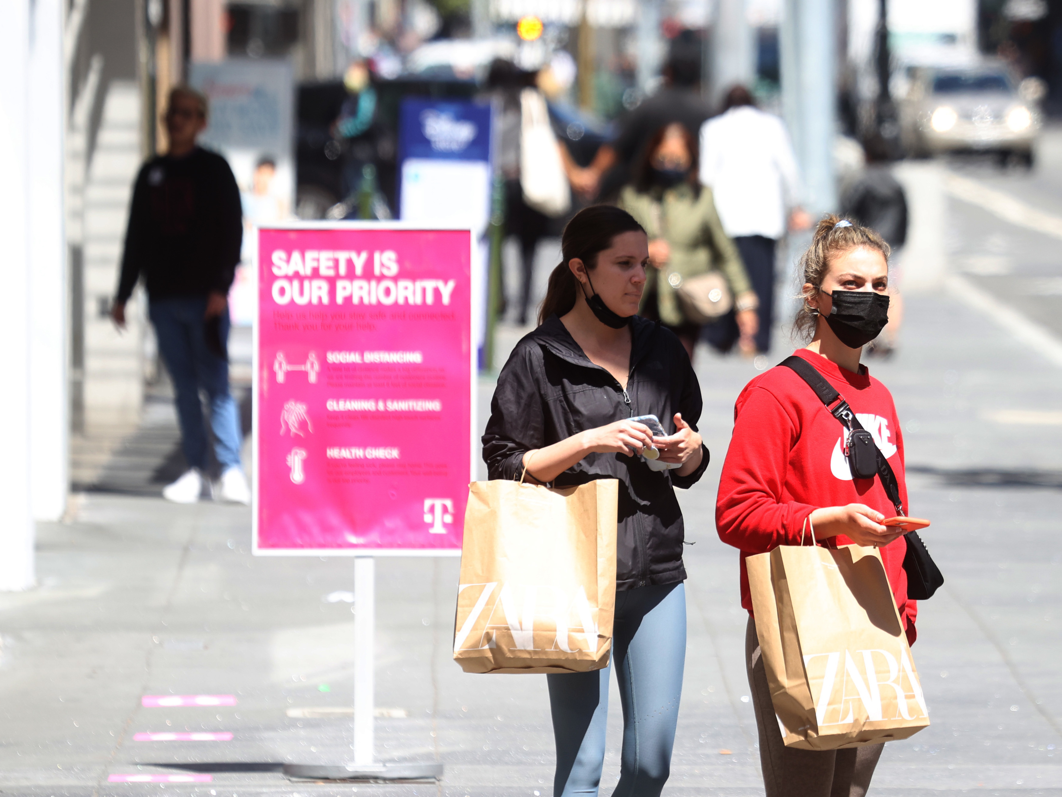 caption: Pedestrians carry shopping bags as they walk through the Union Square shopping district on April 15 in San Francisco. Data on Friday showed personal income jumped 21.1% last month, in what was the largest increase on record.