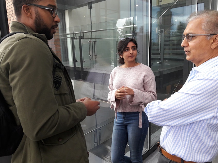 caption: Professor Suresh Kotha (right) speaks with business school students at the University of Washington.