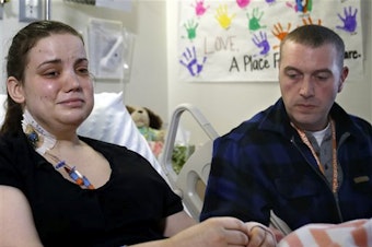 caption: Washington mudslide survivor Amanda Skorjanc, left, talks to the media with her partner Ty Suddarth at Harborview Medical Center, April 9, 2014, in Seattle. On March 22, Skorjanic said she was trapped in a pocket formed by her broken couch and pieces of her roof with her infant son.
