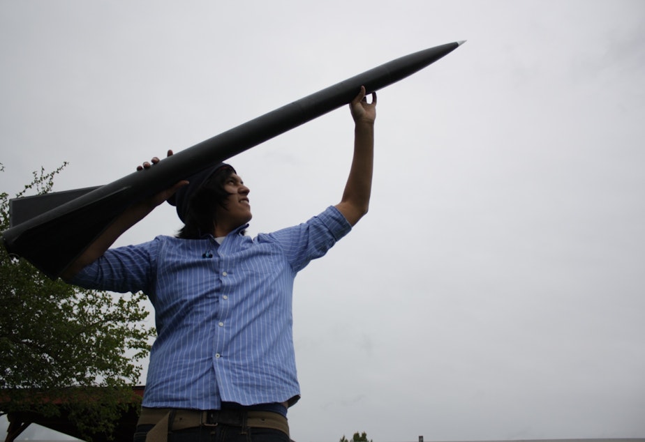 caption: Christian Cultee, a student at the Northwest Indian College, with a rocket that broke the sound barrier.