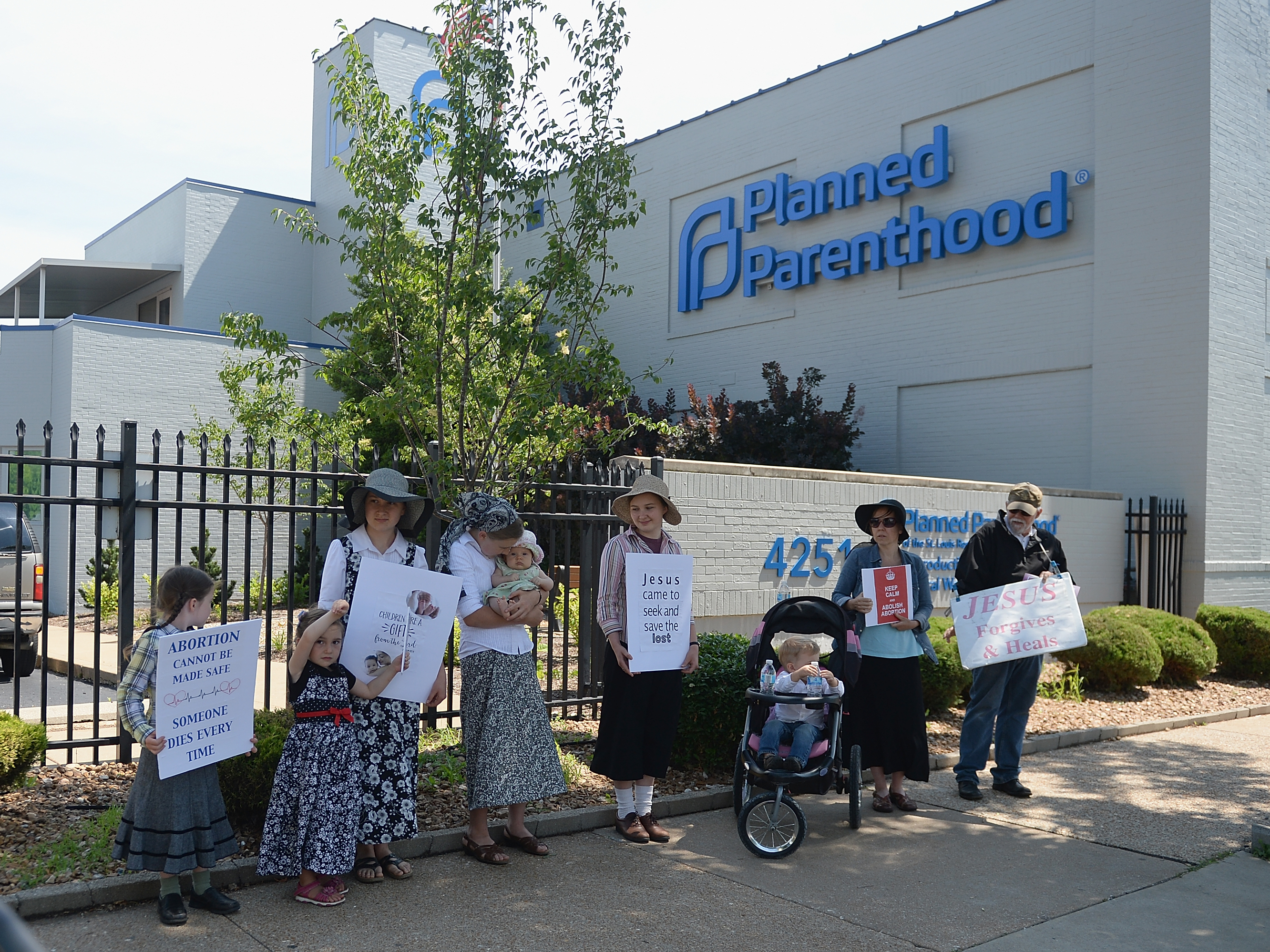caption: A group of anti-abortion rights protesters hold signs during a rally outside a Planned Parenthood Reproductive Health Center in St Louis, Mo., in June.