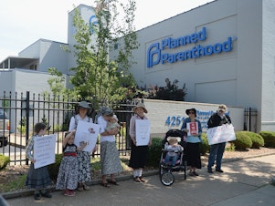 caption: A group of anti-abortion rights protesters hold signs during a rally outside a Planned Parenthood Reproductive Health Center in St Louis, Mo., in June.