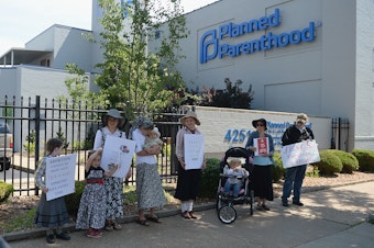 caption: A group of anti-abortion rights protesters hold signs during a rally outside a Planned Parenthood Reproductive Health Center in St Louis, Mo., in June.