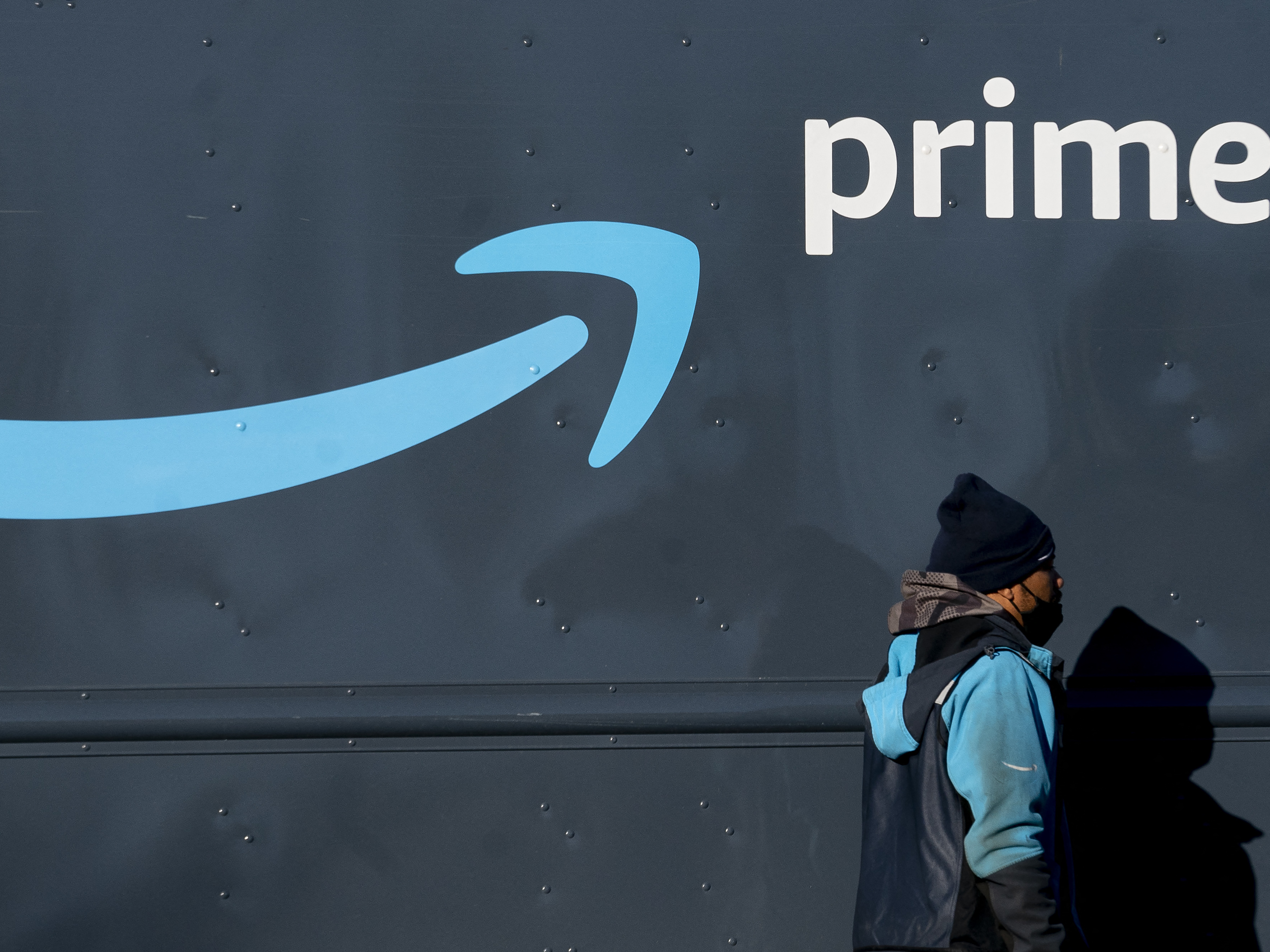 An Amazon worker walks past his Amazon Prime delivery truck in Washington, DC, on February 19, 2022.