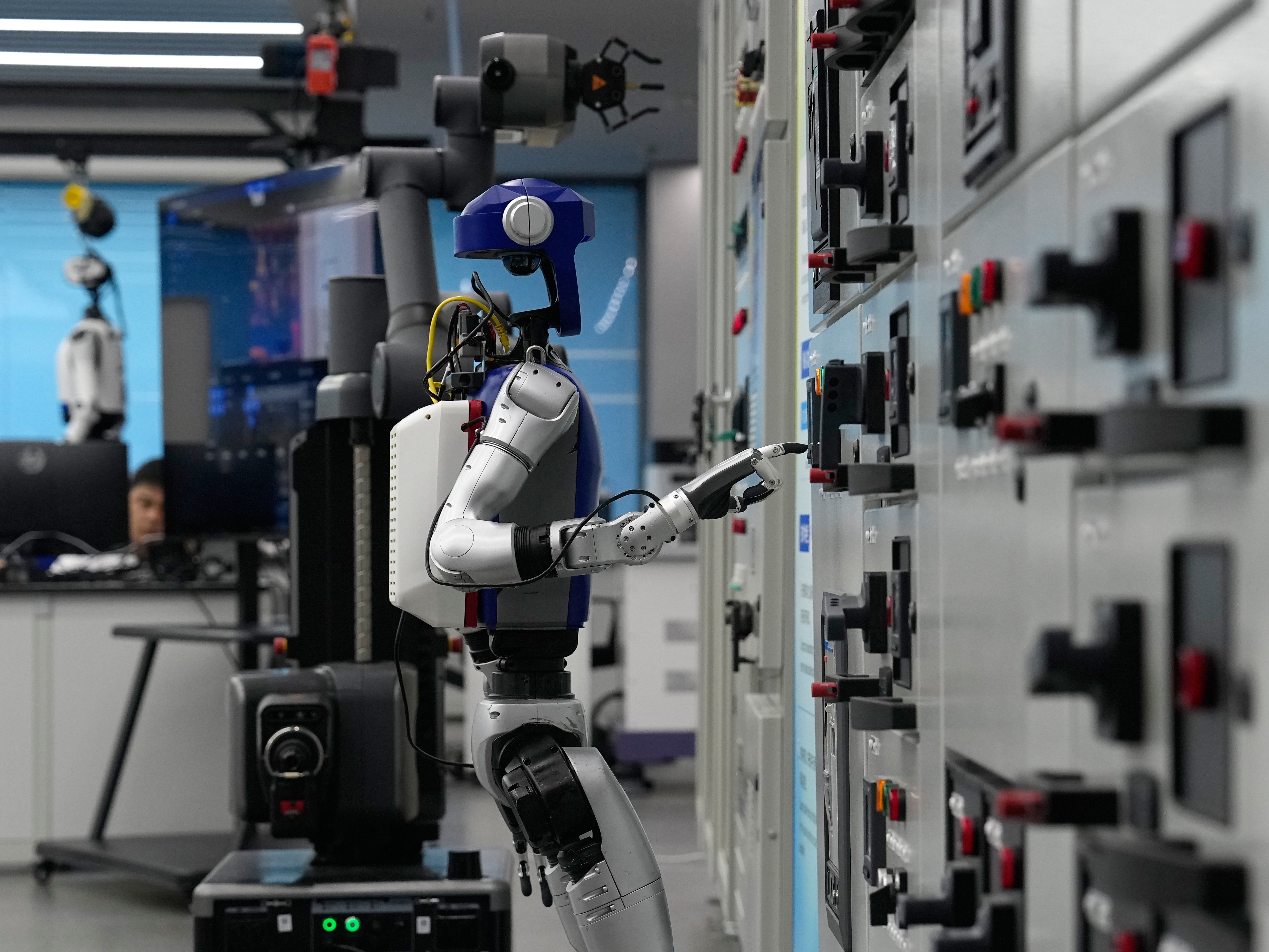 caption: Artificial Intelligence robots demonstrate working on power grid control units during a media organized tour at Guangdong Power Grid Robotics Laboratory in Guangzhou, in southern China's Guangdong province, on April 16.