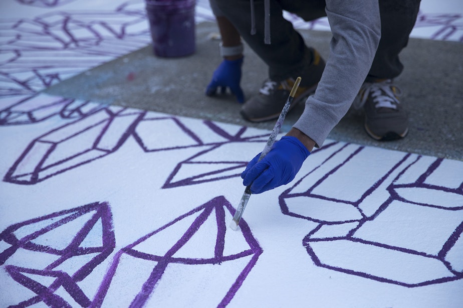 caption: Jason Huff helps mixed media artist Future Crystals paint the letter E in the Black Lives Matter street mural on Friday, October 2, 2020, on E. Pine Street in Seattle.