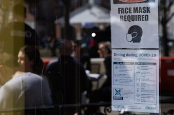 caption: A sign requiring face masks and COVID-19 protocols is displayed at a restaurant in Plymouth, Mich., on March 21. Coronavirus cases in Michigan are skyrocketing after months of steep declines, one sign that a new surge may be starting.