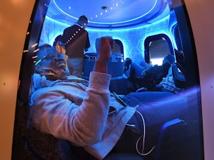 caption: Participants sit a Blue Origin space simulator during a conference on robotics and artificial intelligence in Las Vegas on June 5, 2019. On Saturday, Blue Origin announced that an unidentified bidder will pay $28 million for a suborbital flight on the company's New Shepard vehicle.