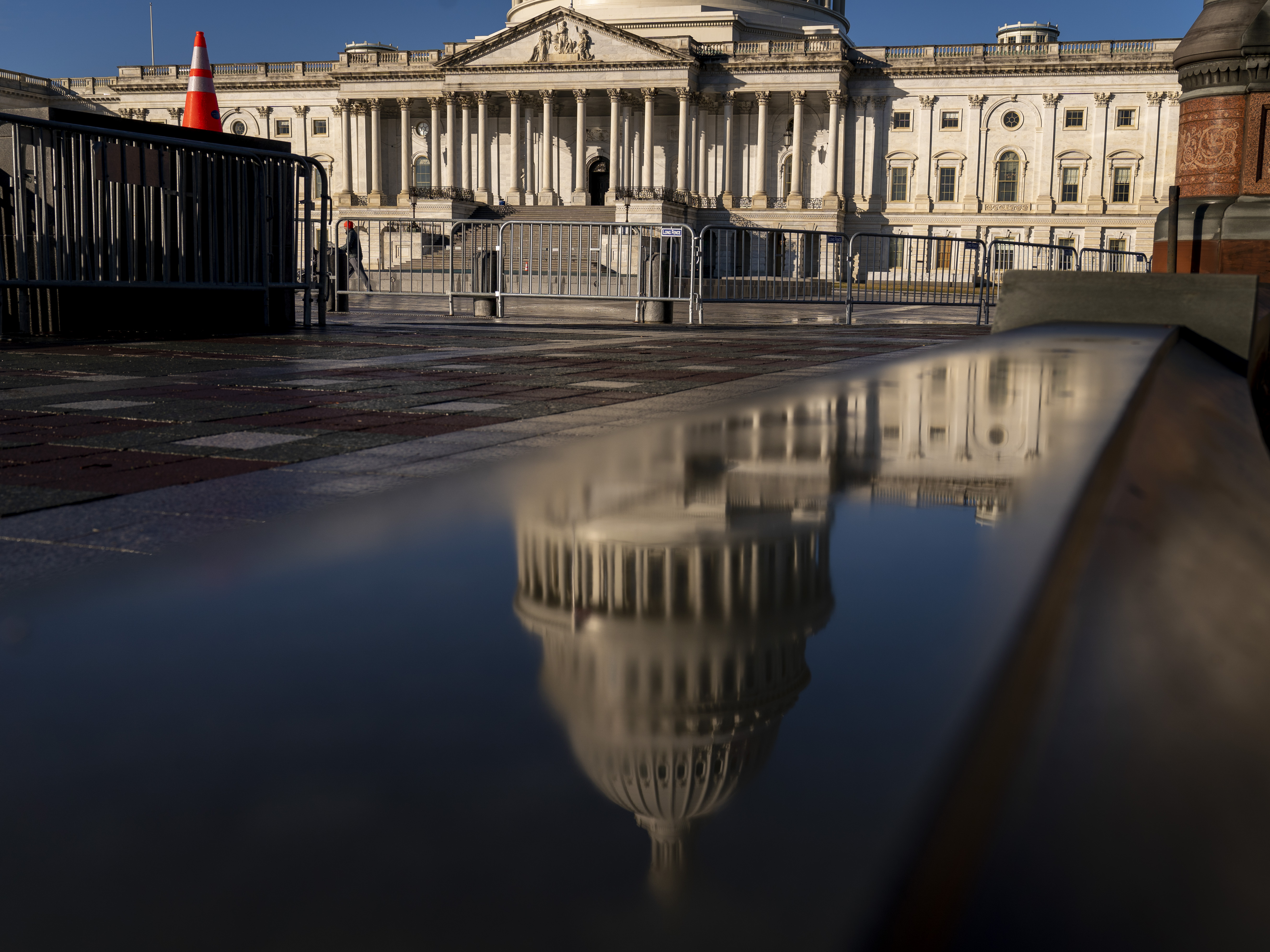 caption: The Dome of the U.S. Capitol Building is visible in a reflection on Capitol Hill on Jan. 23, 2023.