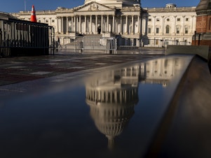 caption: The Dome of the U.S. Capitol Building is visible in a reflection on Capitol Hill on Jan. 23, 2023.
