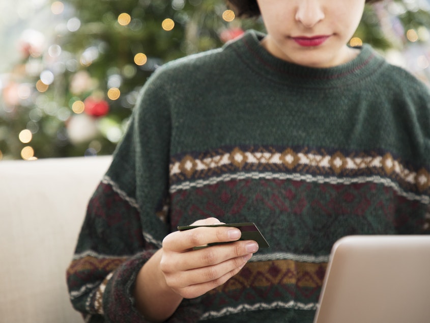 A computer user is shown in front of a laptop, holding a credit card.